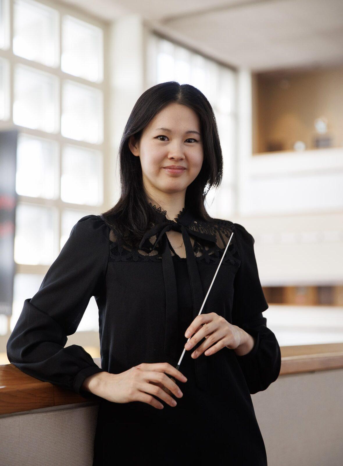 Conductor Monica Chen holding a baton.